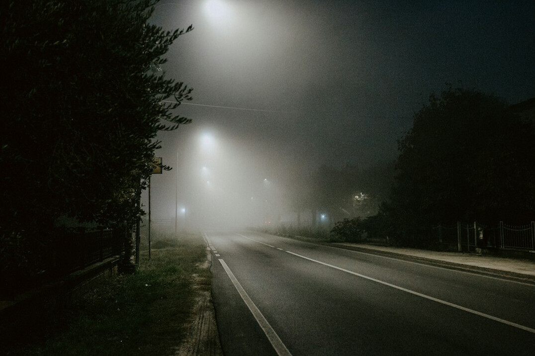 Empty foggy street at night under a streetlight
